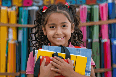 Smiling young girl with new school supplies